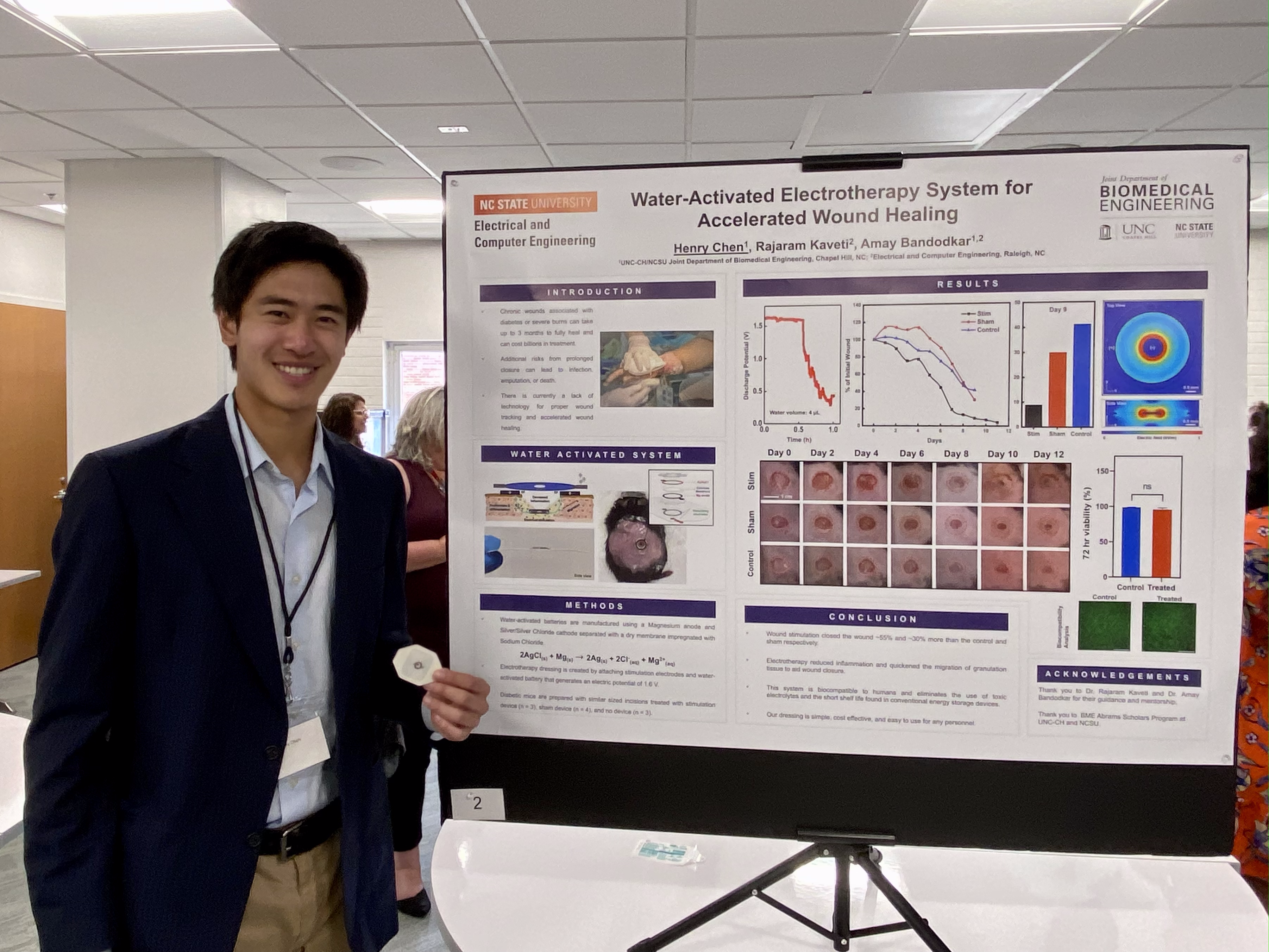 Henry standing in front of a research poster along with WPED device
